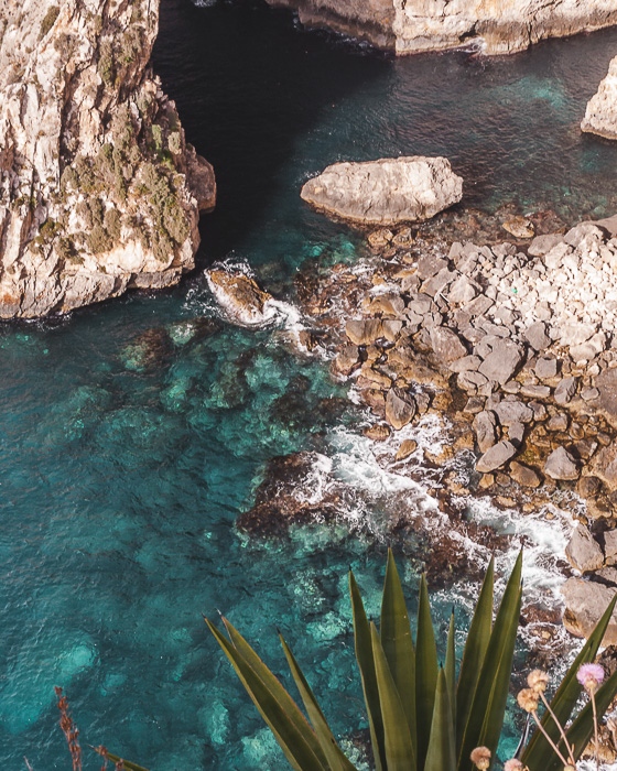 Malta travel guide crystal clear water of Blue Grotto by Dancing the Earth