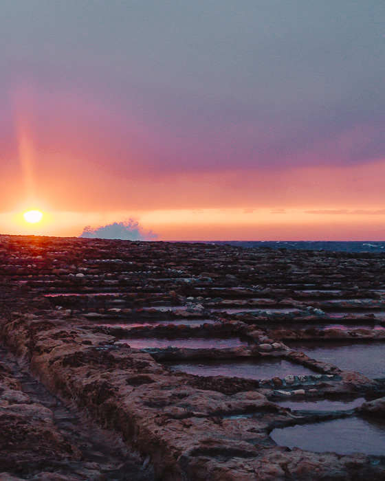 Malta travel guide Gozo island Ghajn Barrani salt pans at sunset with waves by Dancing the Earth
