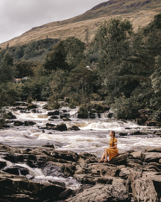 Falls of Dochart sitting on a rock in the river by Dancing the Earth